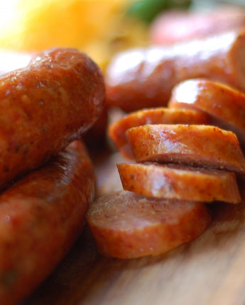 summer sausage cooked and sliced on a wooden cutting board