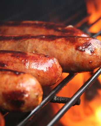 chili dogs cooking on a grill with flames