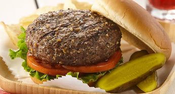 Hamburger with bun, tomatoes, and lettuce with a side of pickles