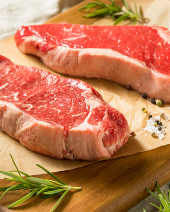 Raw cuts of steaks on a wooden cutting board