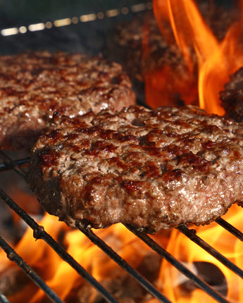 Cooking hamburger patties on the grill with flames