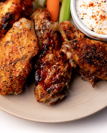 plate of grilled meats served with a side of dip and celery and carrots