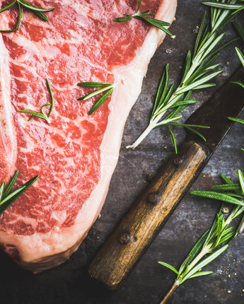 Cut of raw steak beside garnish and knife