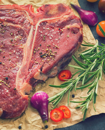 Raw steak with seasonings and garnishes on a brown parchment paper